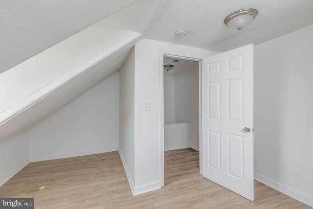 additional living space featuring light wood-type flooring and vaulted ceiling