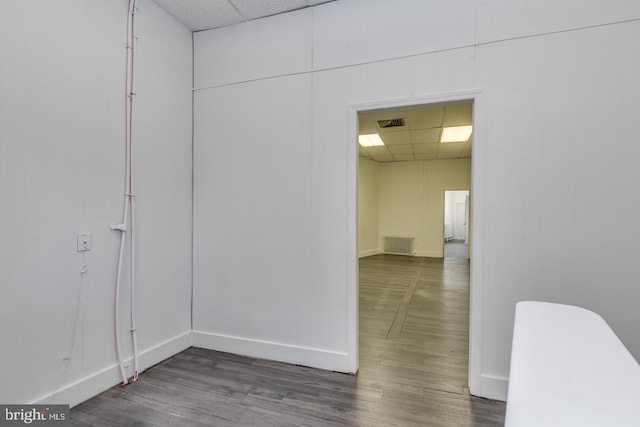 hall with a drop ceiling and dark wood-type flooring