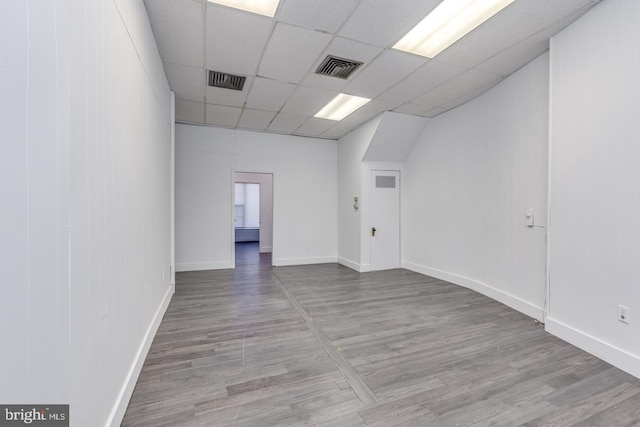 unfurnished room with hardwood / wood-style floors and a drop ceiling