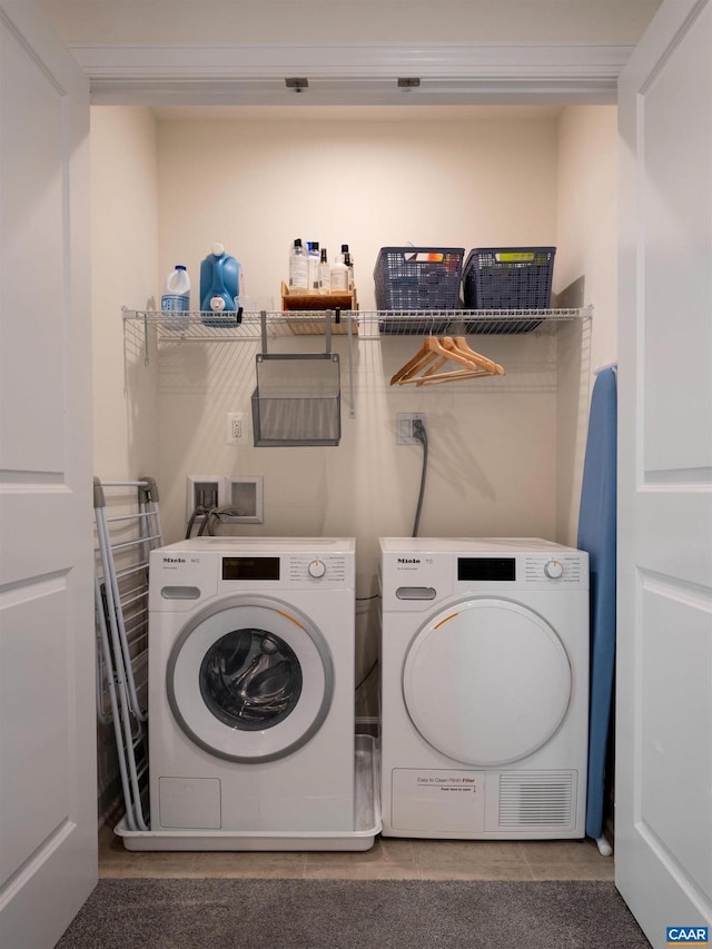 laundry area featuring washing machine and clothes dryer and tile patterned flooring