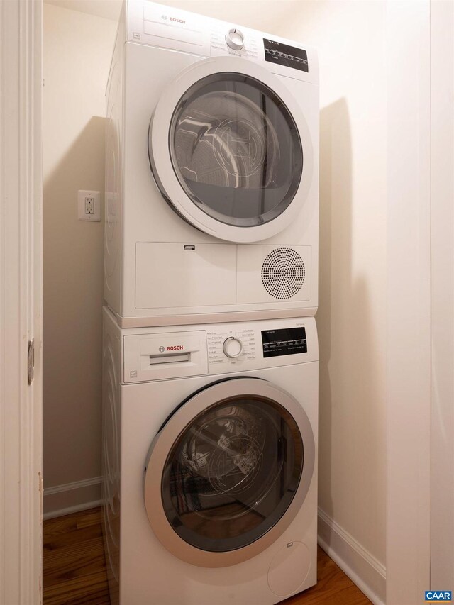 laundry area featuring wood-type flooring and stacked washer / dryer