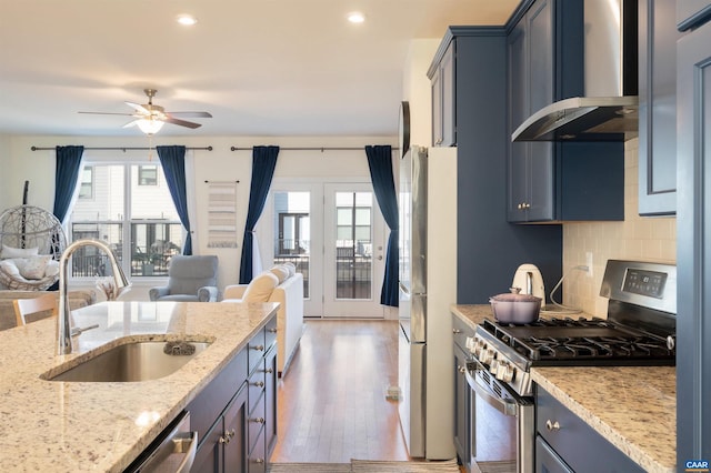 kitchen featuring light stone countertops, appliances with stainless steel finishes, dark hardwood / wood-style flooring, wall chimney exhaust hood, and sink