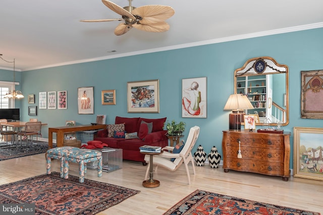 living room featuring hardwood / wood-style floors, ceiling fan with notable chandelier, and crown molding