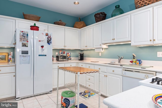 kitchen with light tile patterned floors, white appliances, white cabinetry, and sink