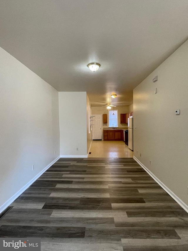 empty room featuring ceiling fan, sink, and dark wood-type flooring