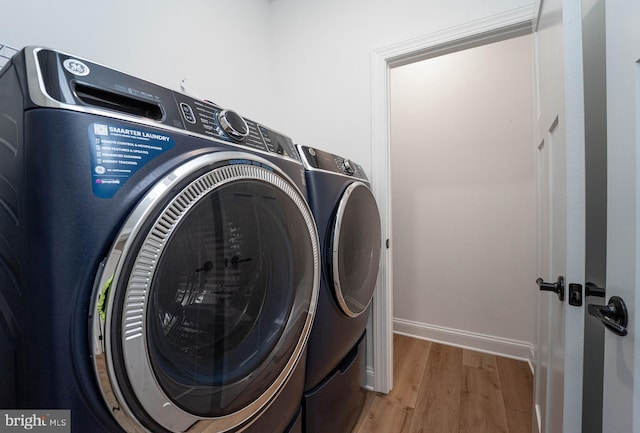 laundry area with independent washer and dryer and light wood-type flooring