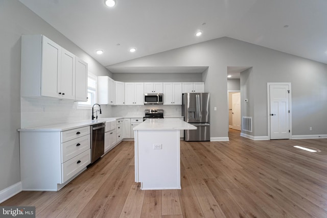 kitchen featuring a center island, stainless steel appliances, light hardwood / wood-style floors, lofted ceiling, and white cabinets