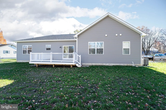 back of property featuring central AC unit, a wooden deck, and a lawn