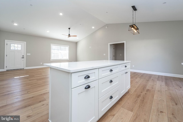 kitchen with light wood-type flooring, ceiling fan, white cabinets, a kitchen island, and lofted ceiling