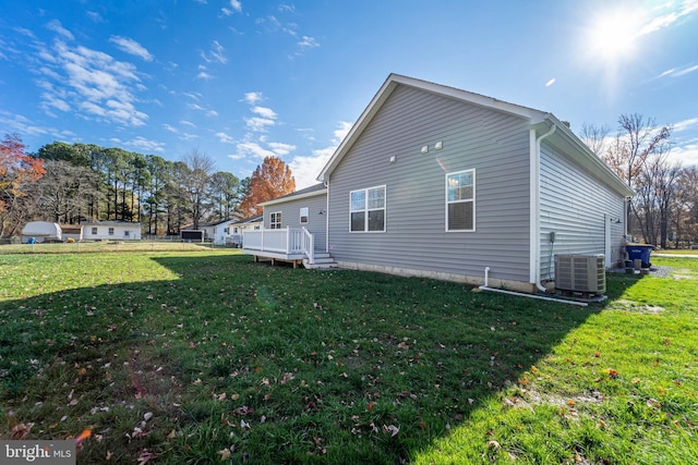 view of side of home with a yard, a wooden deck, and central AC