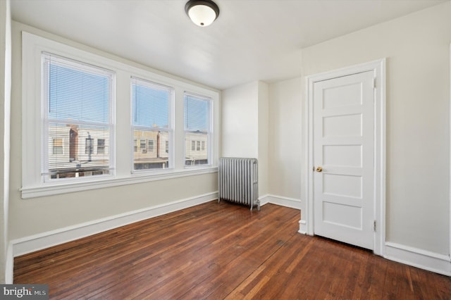 empty room featuring radiator and dark wood-type flooring