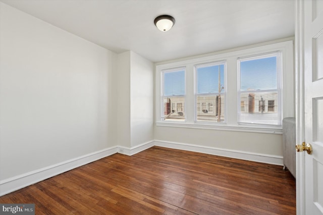 unfurnished room featuring a healthy amount of sunlight and dark hardwood / wood-style flooring