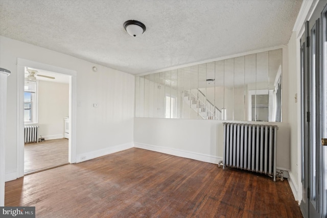 spare room with a textured ceiling, dark wood-type flooring, and radiator