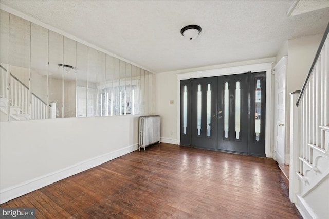 entrance foyer with radiator, dark wood-type flooring, and a textured ceiling