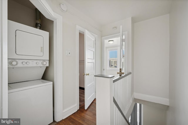 laundry room with dark hardwood / wood-style flooring and stacked washing maching and dryer