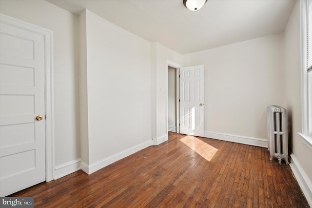 empty room with radiator and dark hardwood / wood-style flooring