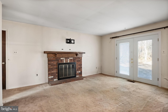 unfurnished living room featuring french doors, light colored carpet, and a brick fireplace