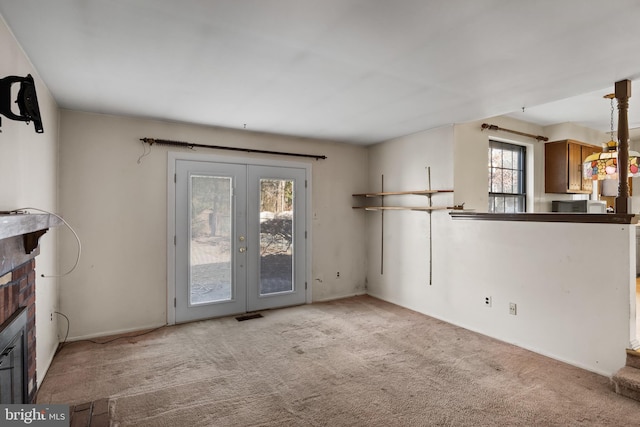 unfurnished living room featuring light carpet and french doors