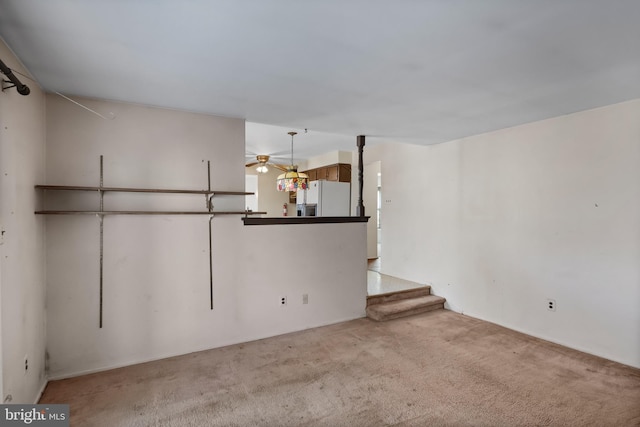 unfurnished living room featuring light carpet and ceiling fan