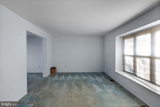 spare room with dark carpet and plenty of natural light