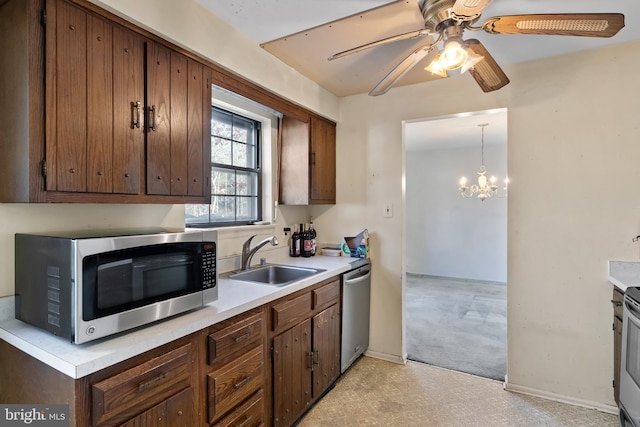 kitchen featuring pendant lighting, ceiling fan with notable chandelier, sink, and stainless steel appliances