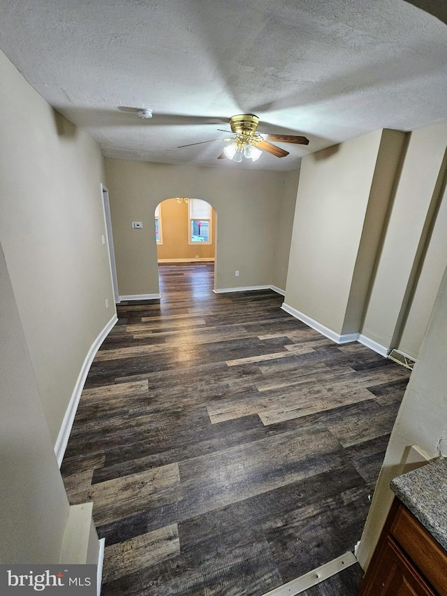 spare room with a textured ceiling, ceiling fan, and dark wood-type flooring