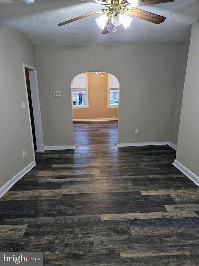 spare room with a textured ceiling, ceiling fan, and dark wood-type flooring