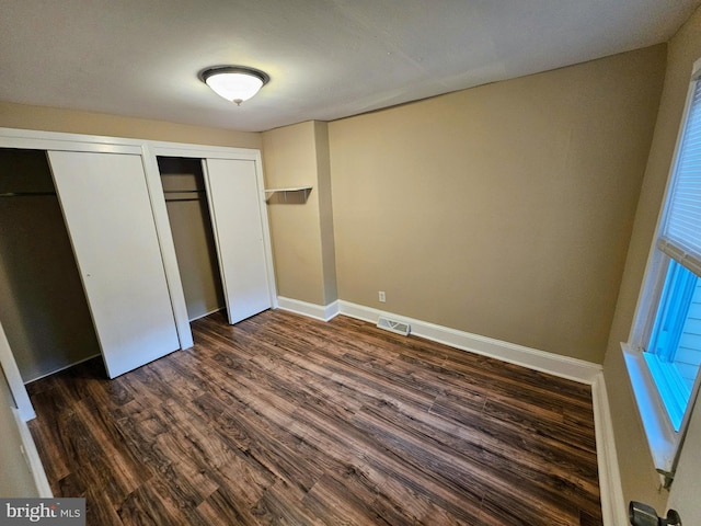 unfurnished bedroom with multiple closets and dark hardwood / wood-style floors