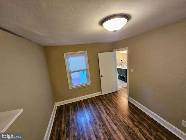 unfurnished room featuring a textured ceiling and dark hardwood / wood-style flooring