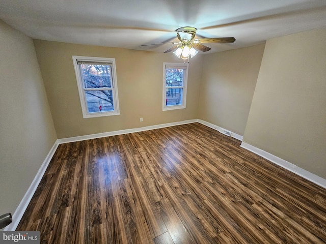 empty room with ceiling fan and dark hardwood / wood-style flooring