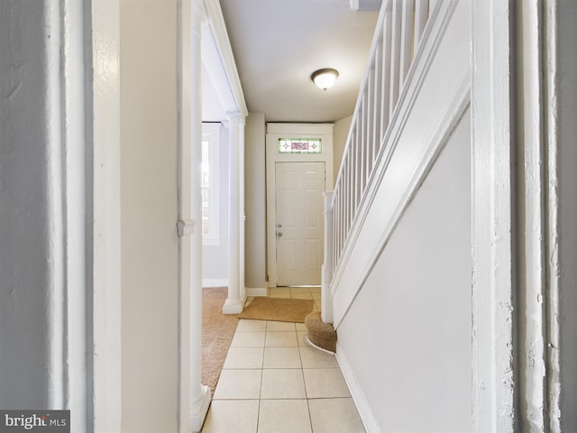 doorway with light tile patterned floors and decorative columns