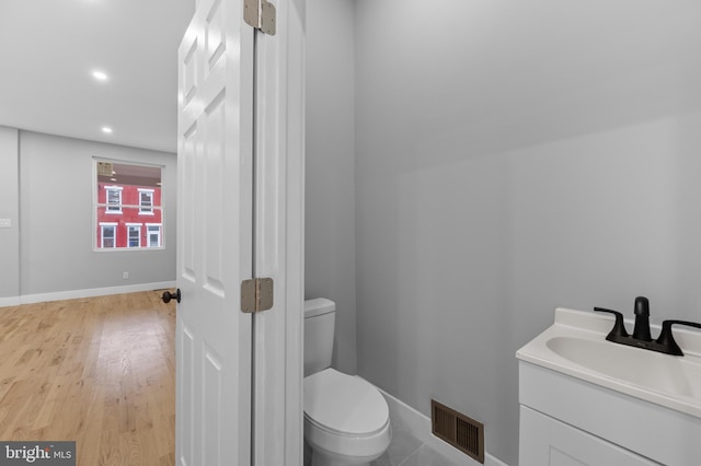 bathroom with hardwood / wood-style floors, vanity, and toilet