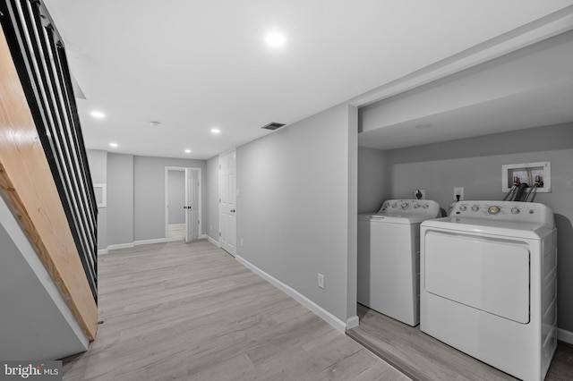 laundry area with washing machine and clothes dryer and light wood-type flooring