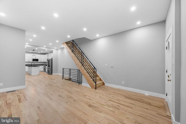 unfurnished living room with light wood-type flooring and sink