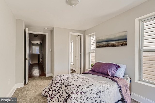 bedroom with multiple windows, ensuite bath, and light colored carpet