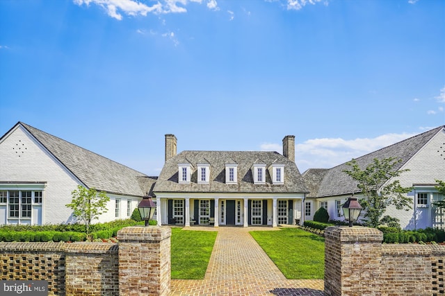 cape cod house with covered porch and a front yard