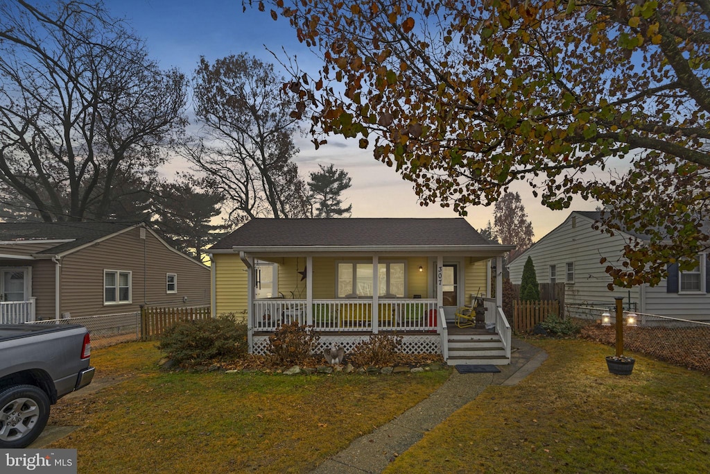 bungalow-style house featuring covered porch and a yard