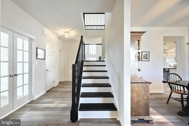 stairs with hardwood / wood-style floors and french doors