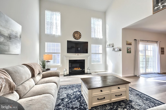 living room featuring plenty of natural light, light wood-type flooring, and a high ceiling