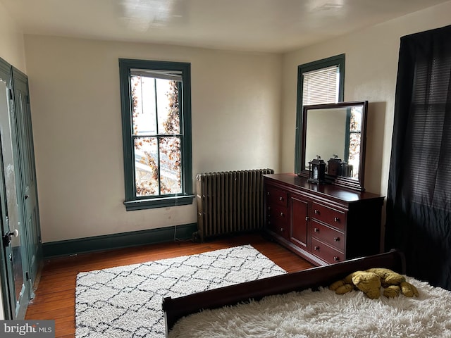 bedroom with hardwood / wood-style flooring and radiator