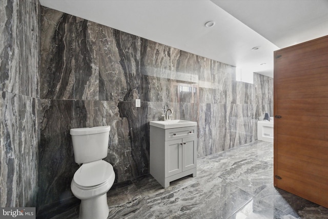 bathroom featuring vanity, tile walls, and toilet