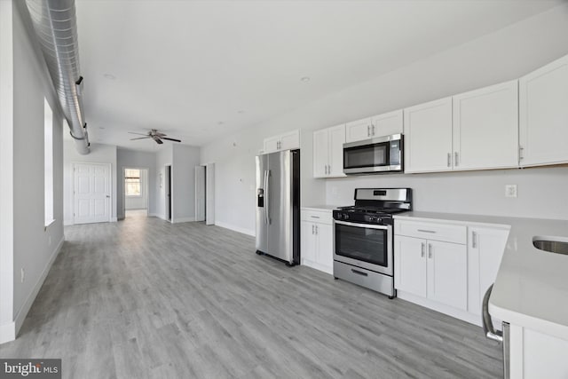 1939 W Diamond St, Philadelphia, PA 19121 - kitchen with appliances with stainless steel finishes, light wood-type flooring, white cabinets, light countertops, and a ceiling fan