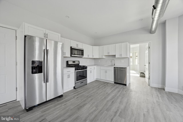 kitchen with sink, white cabinetry, stainless steel appliances, and light hardwood / wood-style flooring