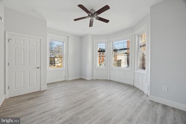 spare room with a wealth of natural light, ceiling fan, and light wood-type flooring