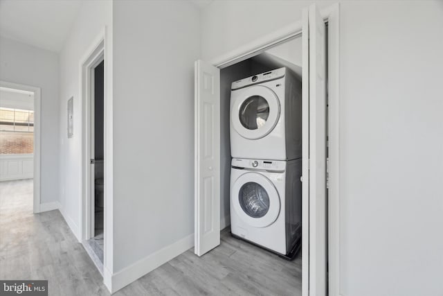 clothes washing area with light hardwood / wood-style floors and stacked washing maching and dryer