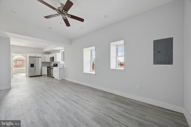 unfurnished living room with electric panel, ceiling fan, light hardwood / wood-style floors, and vaulted ceiling