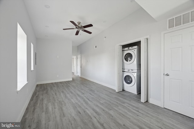 clothes washing area featuring ceiling fan, light wood-type flooring, and stacked washer and clothes dryer