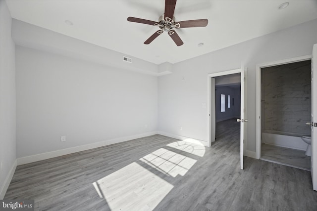 unfurnished bedroom featuring hardwood / wood-style floors, ceiling fan, and connected bathroom