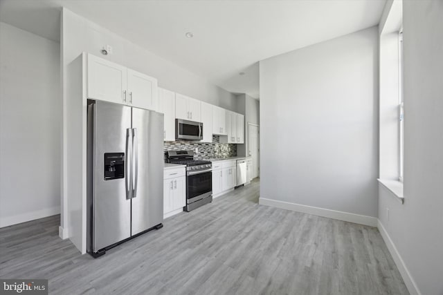 kitchen featuring light hardwood / wood-style floors, white cabinetry, appliances with stainless steel finishes, and tasteful backsplash