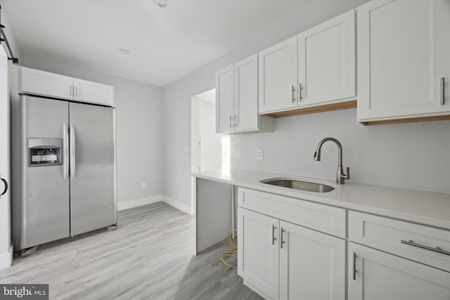 kitchen with sink, white cabinets, light hardwood / wood-style floors, and stainless steel refrigerator with ice dispenser